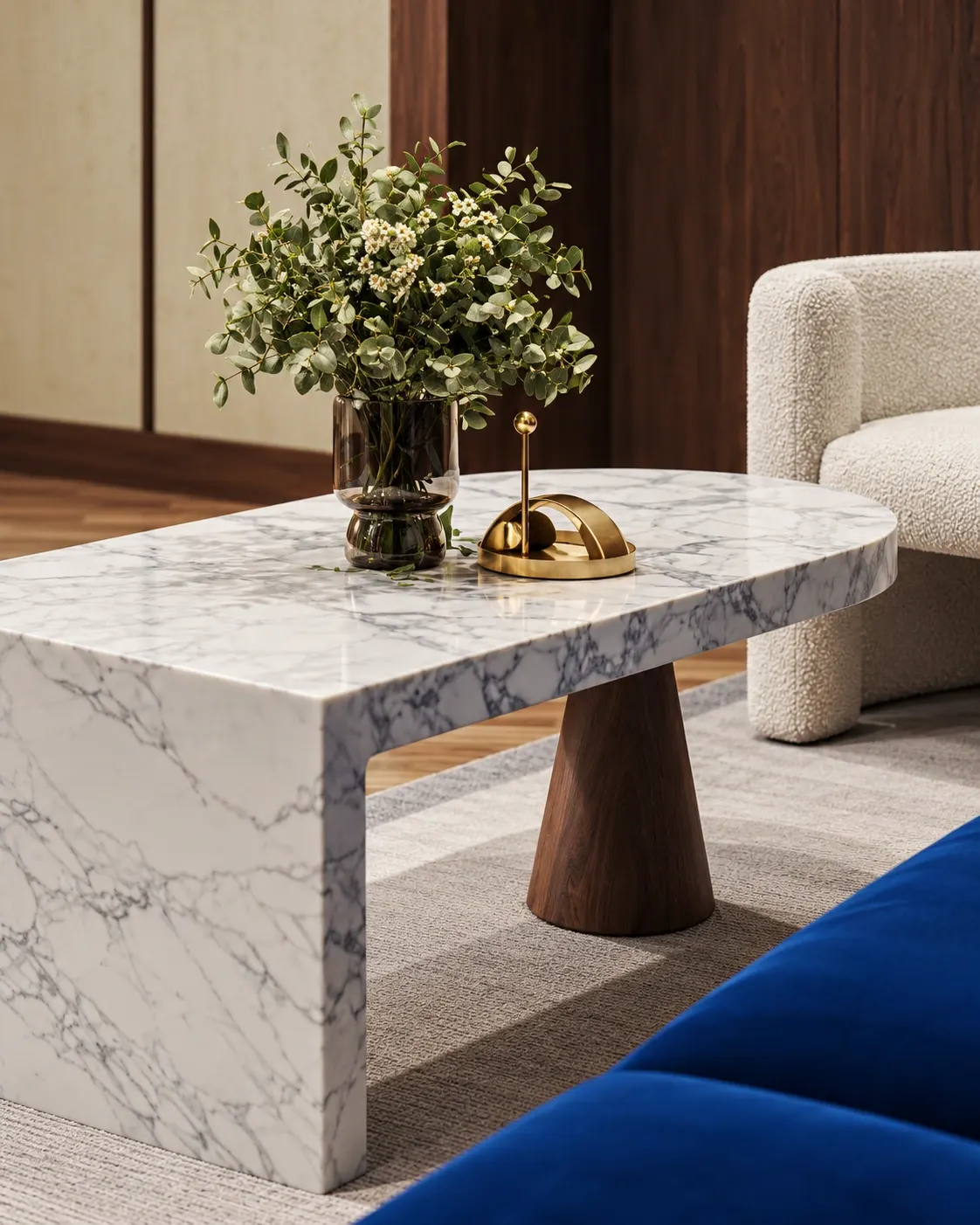 Close-up of a veined stone coffee table with a wooden leg, flowers and gold-toned decor.